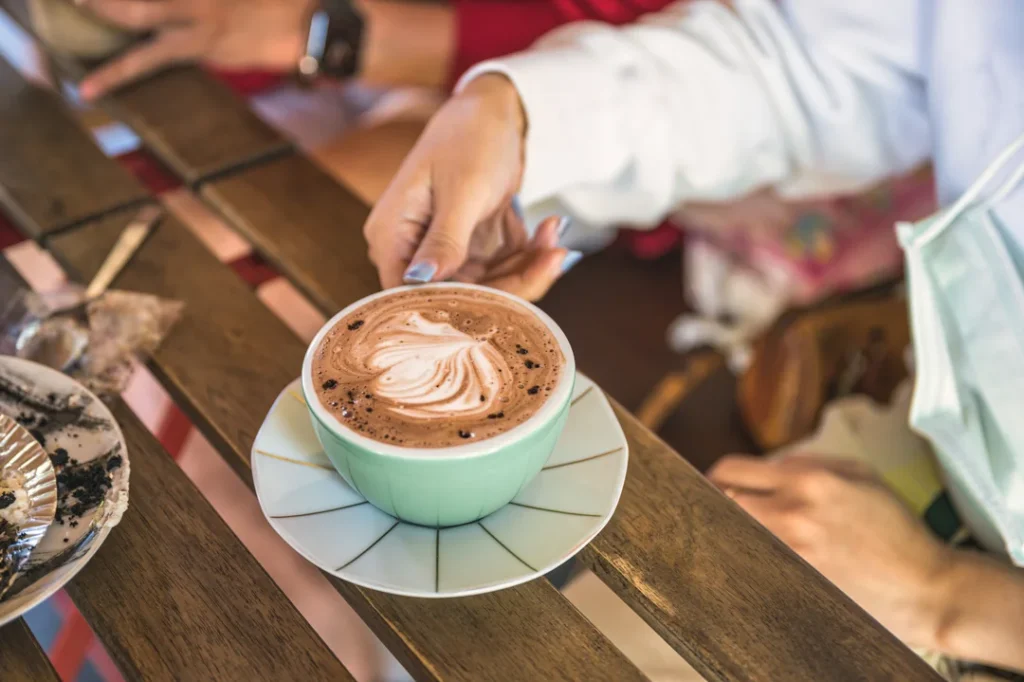 Enjoying Hot Chocolate Drink at a Table Outside